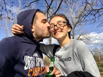 Man kissing woman against bare tree