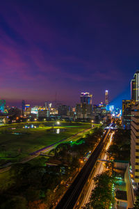 Illuminated park in city against sky at dusk