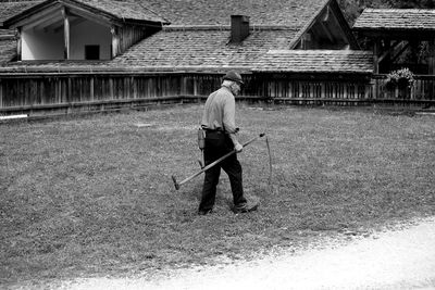 Rear view of man walking on field against building