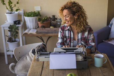 High angle view of woman with pug using typewriter