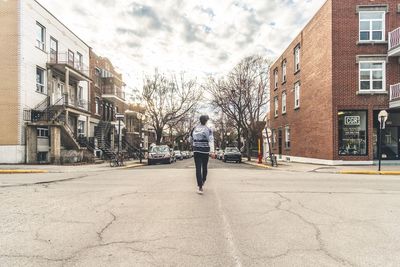 Rear view of man walking on street against buildings