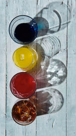 Different coloured drinks in a glass on a white wooden base