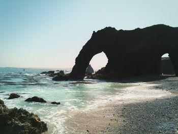Rock formation on beach against clear sky