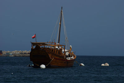 Boat with omani flag on sea against clear sky