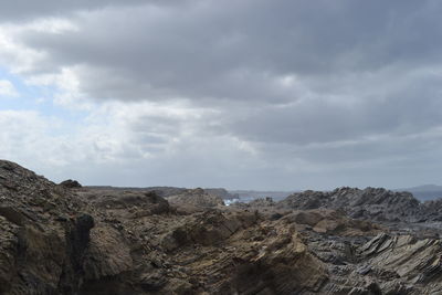 Rocks on mountain against cloudy sky