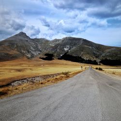 Road by mountain against sky