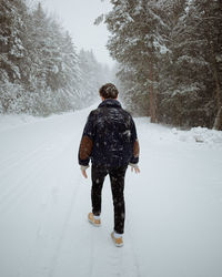 Rear view of man walking on snow covered land