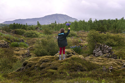 Rear view of woman photographing on landscape against sky