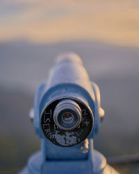 Close-up of coin-operated binoculars against sky during sunset
