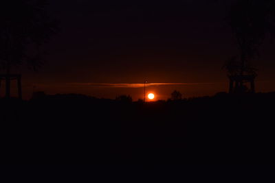Silhouette trees on field against sky at night