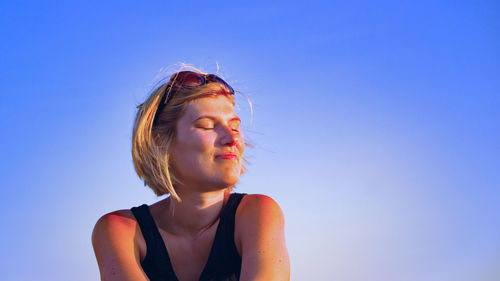 Portrait of a beautiful young woman against blue sky