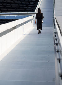 Rear view of woman walking on railing