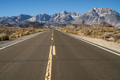 Road leading towards mountains against sky