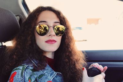 Close-up portrait of young woman wearing sunglasses in car