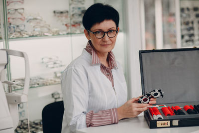 Portrait of woman holding optometry equipment at store