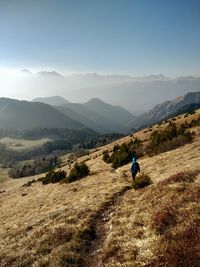 Rear view of man standing on mountain against sky