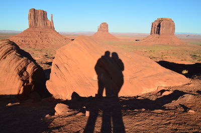Shadow of couple on rock at field in monument valley