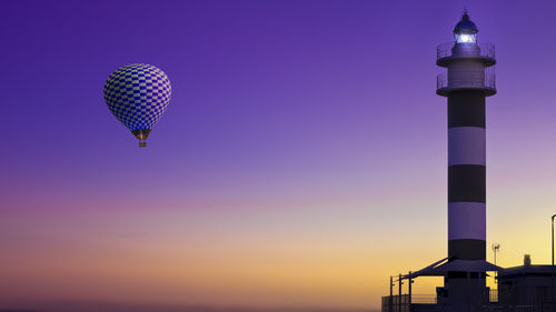 Low angle view of illuminated tower against sky at sunset