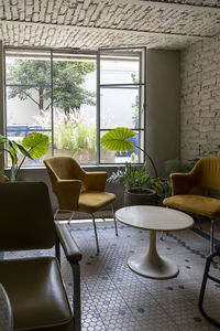 Room, with two yellow armchairs and a table in the center, window with pots and plants, natural