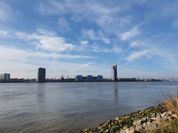 Sea by city buildings against sky