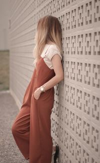 Rear view of young woman standing against wall