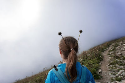 Girl from the back with plant horns on her head in fog in mountains. fun concept, hiking