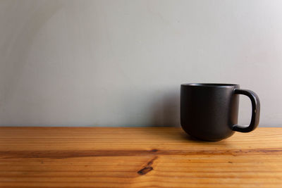 Close-up of coffee cup on table against wall