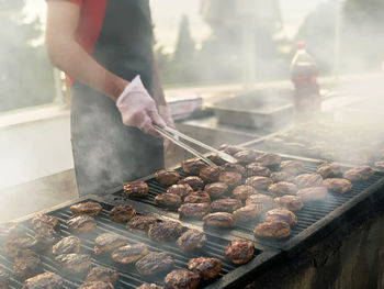 Midsection of man preparing food on barbecue grill