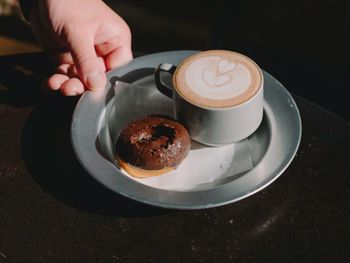 Cropped hand of woman holding coffee on table