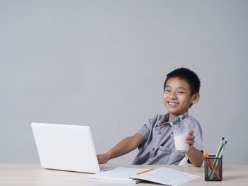 Portrait of smiling young woman using laptop on table