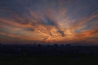 Silhouette buildings against dramatic sky during sunset