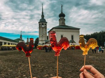 Person holding lollipop against built structure