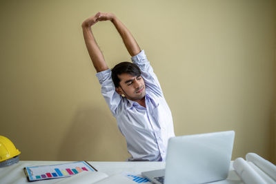 Full length of a boy using mobile phone while standing against wall