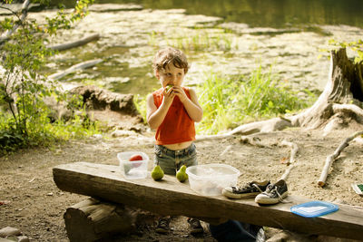 Boy eating pear while standing by lake