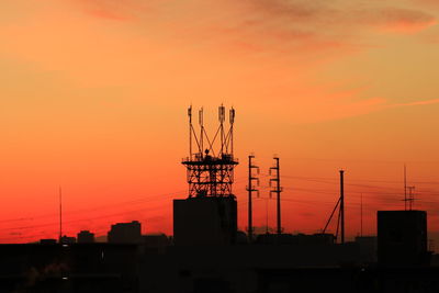 Silhouette cranes at construction site during sunset