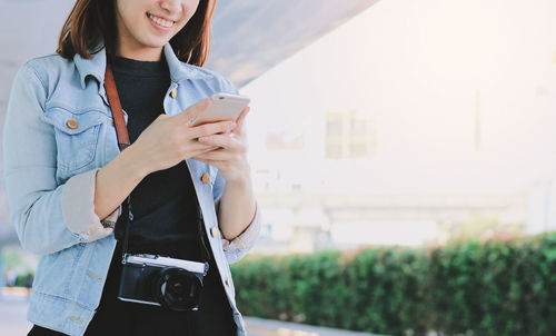 Woman holding mobile phone in city