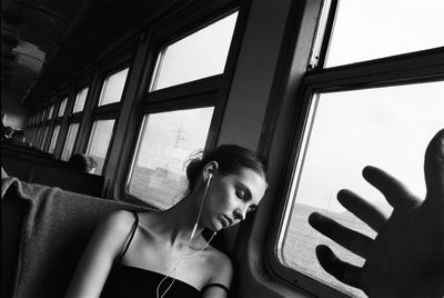 Portrait of young woman looking through window