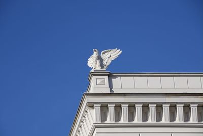 Low angle view of statue against building against clear blue sky