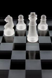 Close-up of glass pieces on chess board against black background