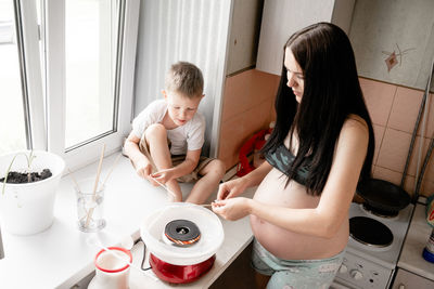 High angle view of pregnant woman with son preparing cotton candies at home