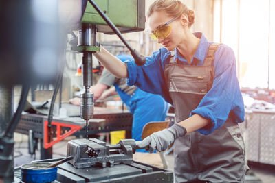 Woman working on machinery at workshop