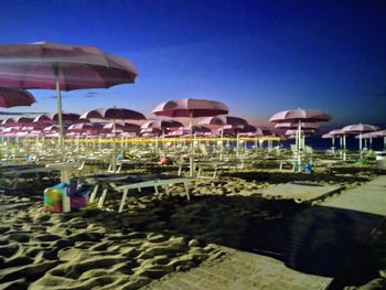 Lounge chairs by swimming pool at beach against clear blue sky