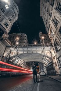 Rear view of man walking on illuminated street at night