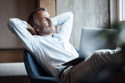 Midsection of man using mobile phone while sitting on sofa at home