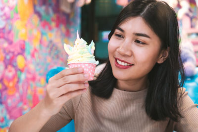 Portrait of woman holding cupcake and smiling