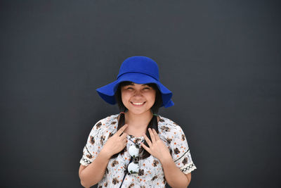 Portrait of smiling young woman against black background