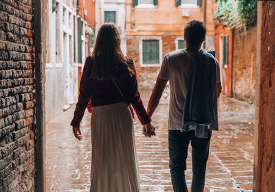 Rear view of people walking on alley in city