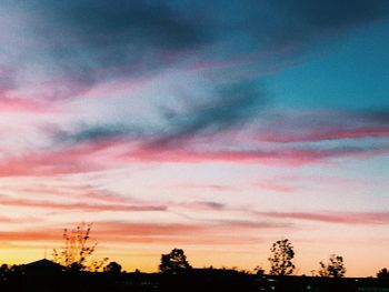 Low angle view of silhouette trees against dramatic sky