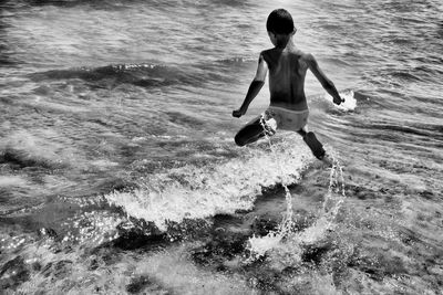 Rear view of shirtless man in sea