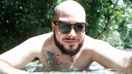 Close-up portrait of young man swimming in lake against trees